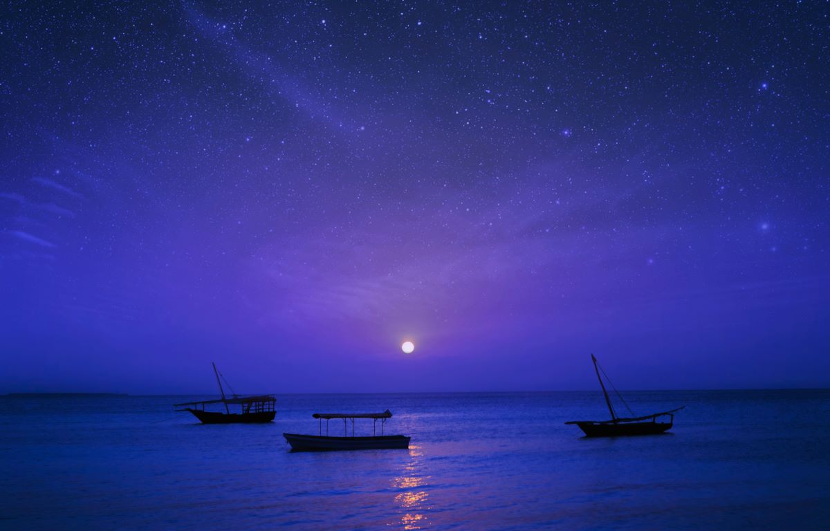 おとぎ話の夜景アフリカ、タンザニア、ザンジバル。海の星空の背景に漁船のシルエット。ブルーからパープルのグラデーションが美しい夜空と水面。